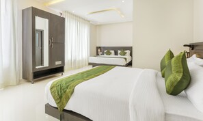 Una habitación de hotel con una cama grande, un armario y una mesita de noche.