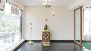 A room with a chandelier, a statue, and a window with a view of trees. - Hotel Sunrise Luxury Stays (Chikkamagaluru)