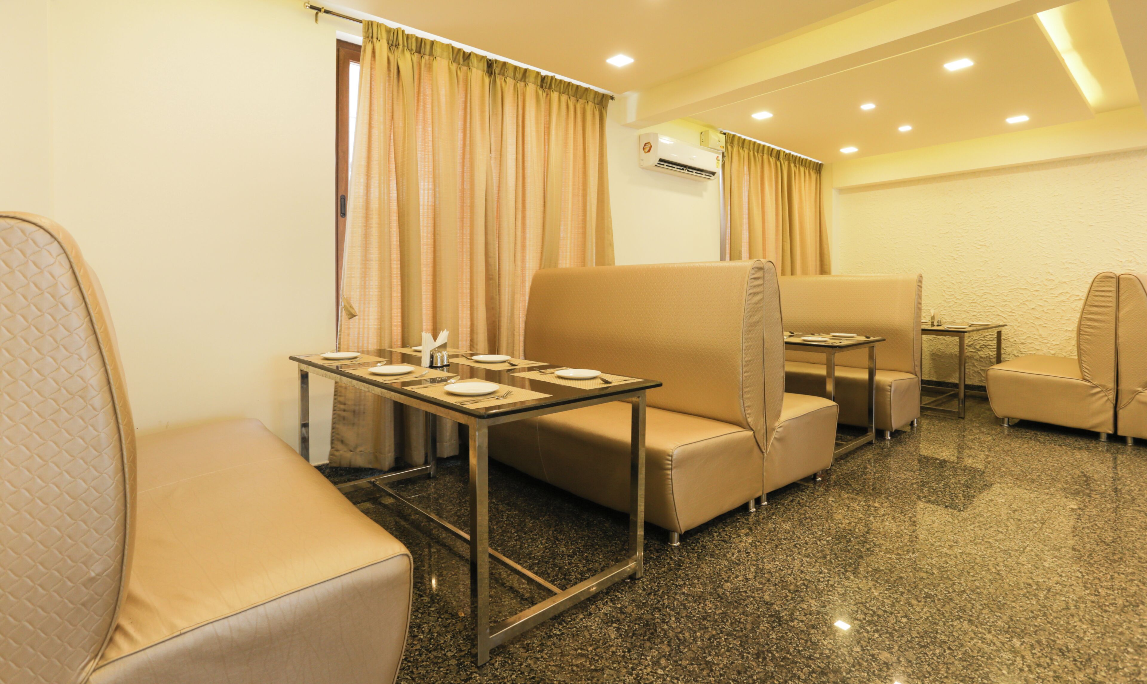 Habitación de hotel con una mesa de comedor para dos personas, un sofá, una mesita y una silla.