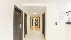 A hallway with doors, a light switch, and a wall-mounted light fixture. - Hotel Sunrise Luxury Stays (Chikkamagaluru)