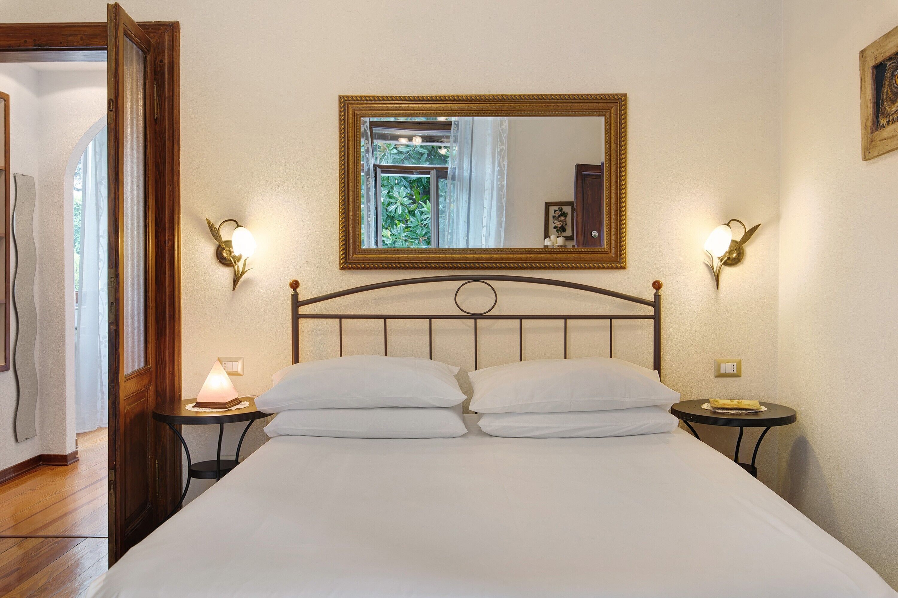 Ein Hotelzimmer mit einem Bett, zwei Nachttischen, einer Ablage, einem Spiegel und Wandleuchten.