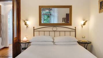 Ein Hotelzimmer mit einem Bett, zwei Nachttischen, einer Ablage, einem Spiegel und Wandleuchten.