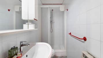 Un bagno moderno con un lavandino bianco, uno specchio, una doccia e un portasciugamani rosso.