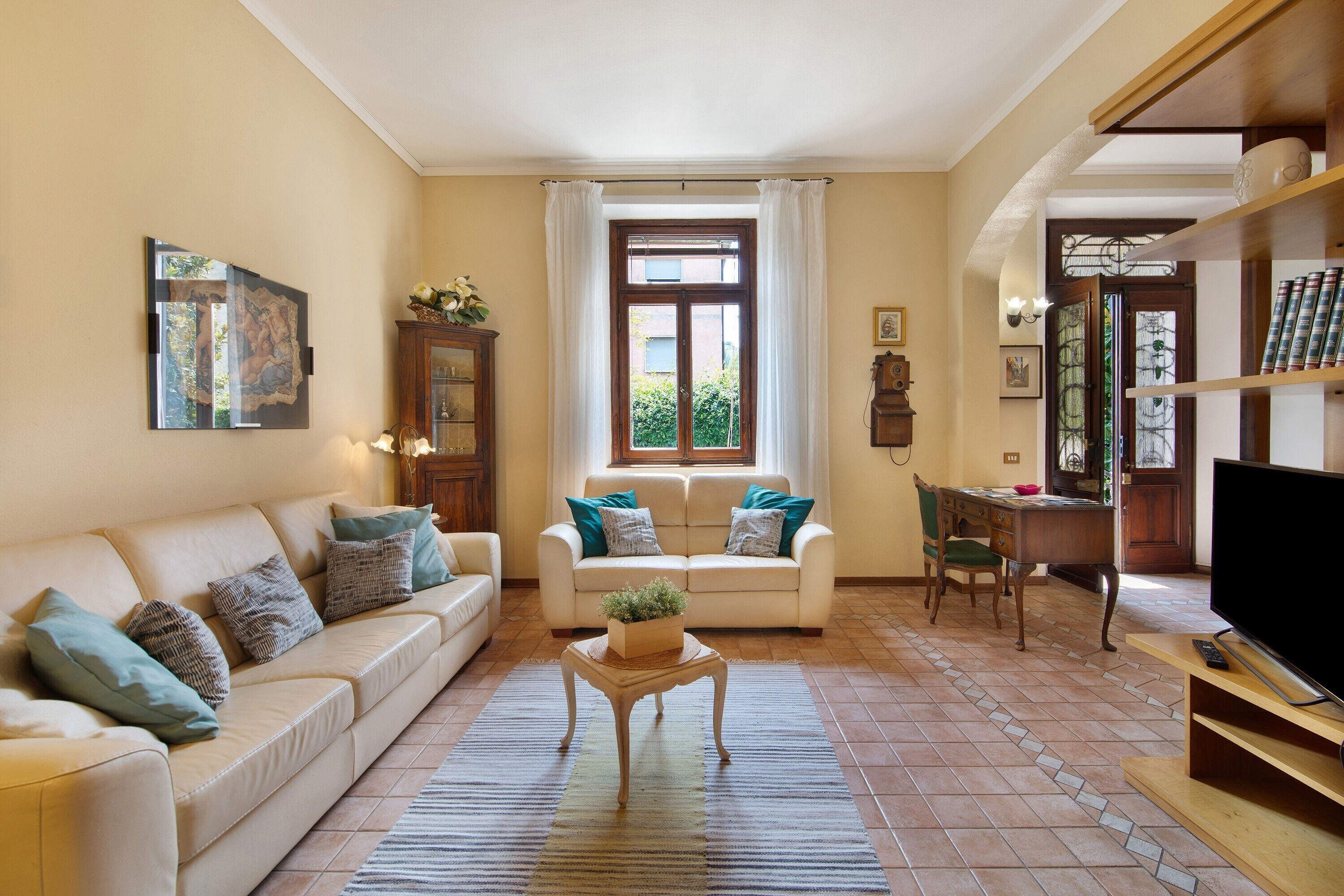 A living room with a sofa, a coffee table, a television, and a bookshelf.