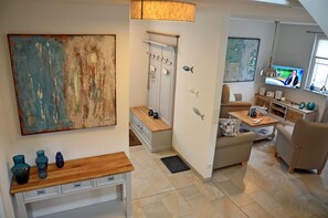 A modern living room with a sofa, a coffee table, and a television. There is a wooden bench with decorative vases and a painting on the wall. - Vacation home with a fireplace and sauna, about 600 meters from the sandy beach; pets welcome (Glowe)