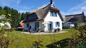 A house with a thatched roof, a white exterior, and blue shutters. - Vacation home with a fireplace and sauna, about 600 meters from the sandy beach; pets welcome (Glowe)