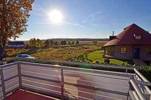 Ein Balkon mit Blick auf eine ländliche Landschaft, ein Auto und ein Gebäude mit rotem Dach.