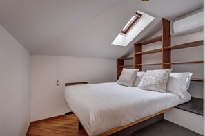 A bedroom with a skylight, a bed with white bedding, and a wooden headboard. - Charming Lake Front Villa Beatrice in Mandello del Lario (Mandello del Lario)