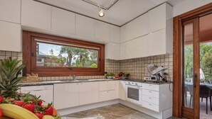 Una cucina moderna con mobili bianchi, forno integrato e finestra vista giardino.