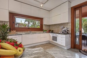 A modern kitchen with white cabinets, a built-in oven, and a window overlooking a garden. - Charming Lake Front Villa Beatrice in Mandello del Lario (Mandello del Lario)