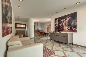 Een ruime woonkamer met een bank, een eettafel en een groot schilderij.