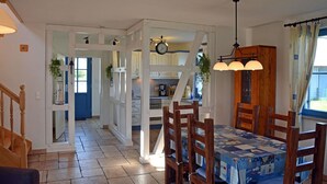 A dining area with a table set for four, a wooden chair, and a hanging light fixture. - Vacation home with a fireplace, about 400 meters from the sandy beach, Wi-Fi, dogs welcome (Glowe)