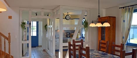 A dining area with a table set for four, a wooden chair, and a hanging light fixture.