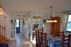 A dining area with a table set for four, a wooden chair, and a hanging light fixture. - Vacation home with a fireplace, about 400 meters from the sandy beach, Wi-Fi, dogs welcome (Glowe)