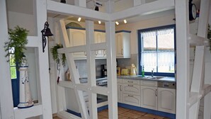 A kitchen with white cabinets, a stove, and a sink. - Vacation home with a fireplace, about 400 meters from the sandy beach, Wi-Fi, dogs welcome (Glowe)
