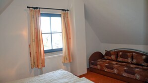 A bedroom with a bed, a window with curtains, and a sofa. - Vacation home with a fireplace, about 400 meters from the sandy beach, Wi-Fi, dogs welcome (Glowe)