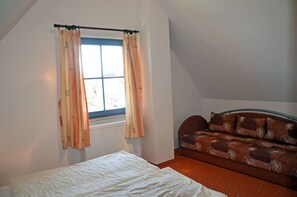 A bedroom with a bed, a window with curtains, and a sofa. - Vacation home with a fireplace, about 400 meters from the sandy beach, Wi-Fi, dogs welcome (Glowe)