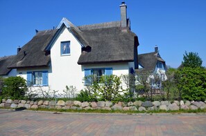 A traditional house with a thatched roof, white walls, and blue shutters. - Vacation home with a fireplace, about 400 meters from the sandy beach, Wi-Fi, dogs welcome (Glowe)