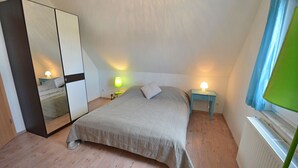 A bedroom with a bed, a wardrobe, bedside lamps, and a window with curtains. - Quiet, central location, about 250 m from the Baltic Sea beach, sunroom (Glowe)