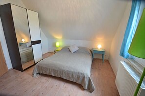 Ein Schlafzimmer mit einem Bett, einem Kleiderschrank, Nachttischlampen und einem Fenster mit Vorhängen.