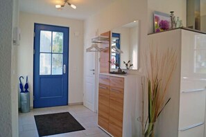 A kitchen with a white refrigerator, wooden cabinets, a blue door, and a black rug. - Vacation home with a fireplace and sauna, about 500 meters from the sandy beach; dogs are welcome (Glowe)
