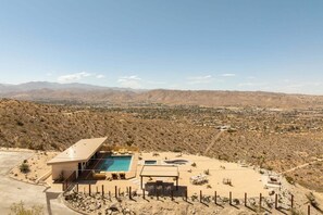 A desert landscape with a modern building featuring a swimming pool and outdoor seating. - Rattlesnake Ranch - Hollywood Retreat w Pool&Views (Yucca Valley)