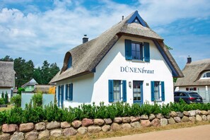 A traditional building with a thatched roof and the name 'DÜNENbraut' on the facade. - Vacation home with a fireplace and sauna, about 500 meters from the sandy beach; dogs allowed (Glowe)