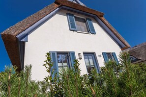 A two-story house with a steeply pitched roof, blue shutters, and a white facade. - Vacation home with a fireplace and sauna, about 500 meters from the sandy beach; dogs are welcome (Glowe)