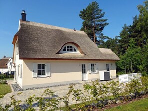 A house with a steeply pitched roof, a small porch, and a white fence in the foreground. - Vacation home with a fireplace, about 800 meters from the sandy beach, with a washing machine and Wi-Fi (Glowe)