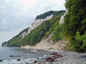A coastal landscape with a rocky beach, cliffs, and dense greenery. - Vacation home with a fireplace, about 800 meters from the sandy beach, with a washing machine and Wi-Fi (Glowe)