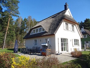 A house with a thatched roof, a patio with outdoor furniture, and a garden. - Vacation home with a fireplace, about 800 meters from the sandy beach, with a washing machine and Wi-Fi (Glowe)