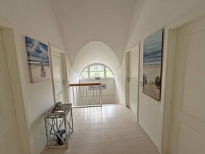 A corridor with arched ceilings, a small table with items, and artwork on the walls. - Vacation home with a fireplace, about 800 meters from the sandy beach, with a washing machine and Wi-Fi (Glowe)