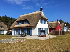A house with a thatched roof, white walls, and blue shutters. - Vacation home with a fireplace and sauna, about 500 meters from the sandy beach; dogs are welcome (Glowe)
