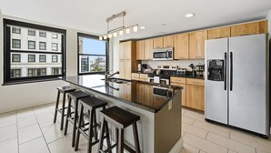 Une cuisine moderne dotée d’un îlot central, d’appareils électroménagers en acier inoxydable et d’armoires en bois.