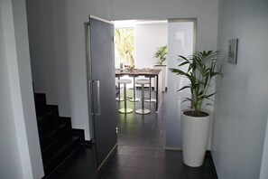 A modern interior with a staircase, a dining area with round tables, and a potted plant. - Very modern vacation home with a sauna, about 200 meters from the sandy beach, Wi-Fi, and a washing machine (Sagard)