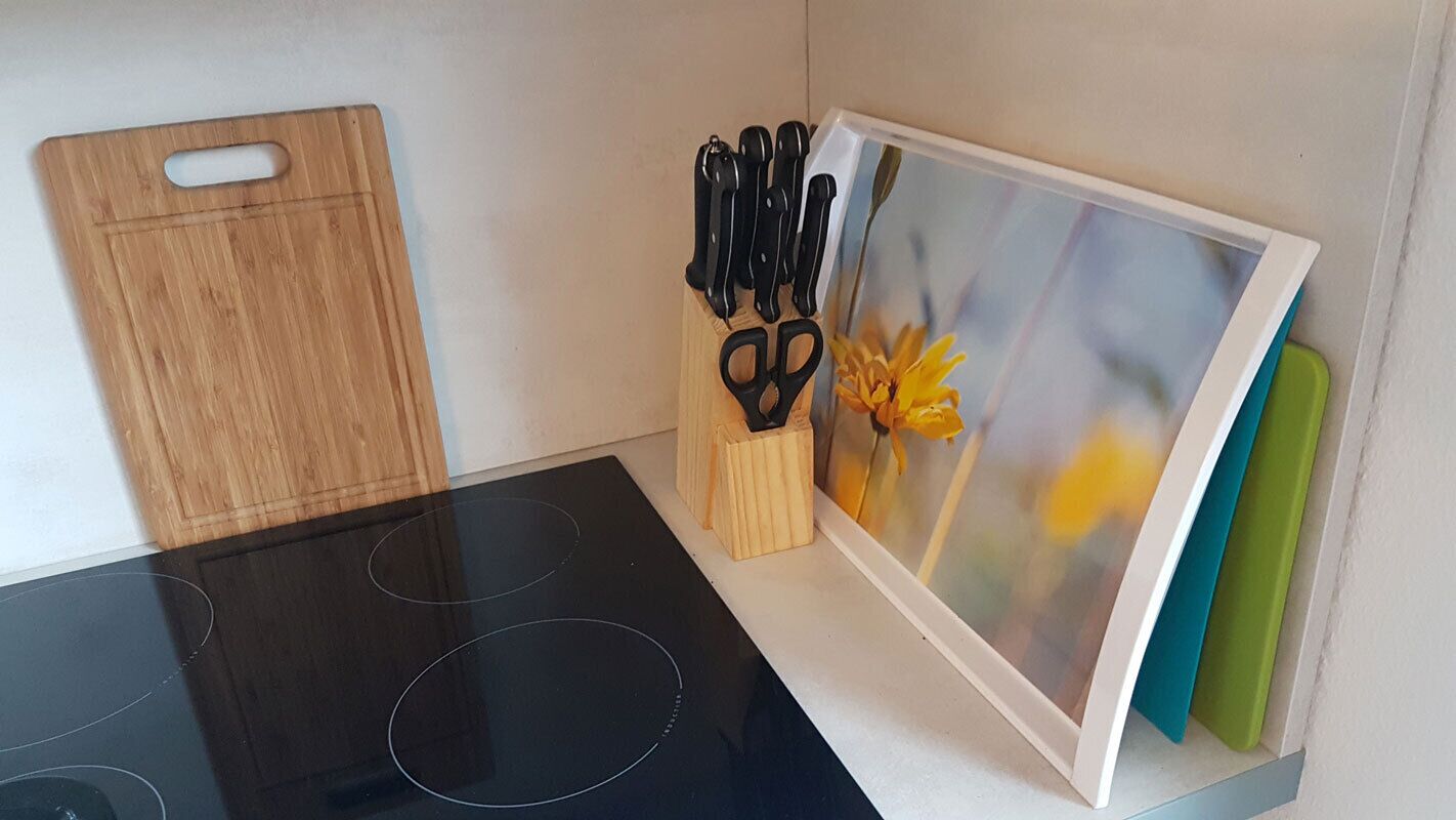 Een keuken met een houten snijplank, een zwart fornuis en een messenblok met schaar.