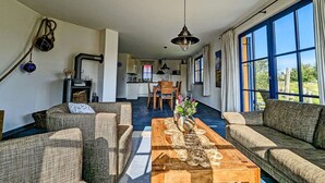 A spacious living room with a fireplace, a dining area, and large windows. - Vacation home with a fireplace and an infrared sauna, about 200 meters from the sandy beach (Glowe)