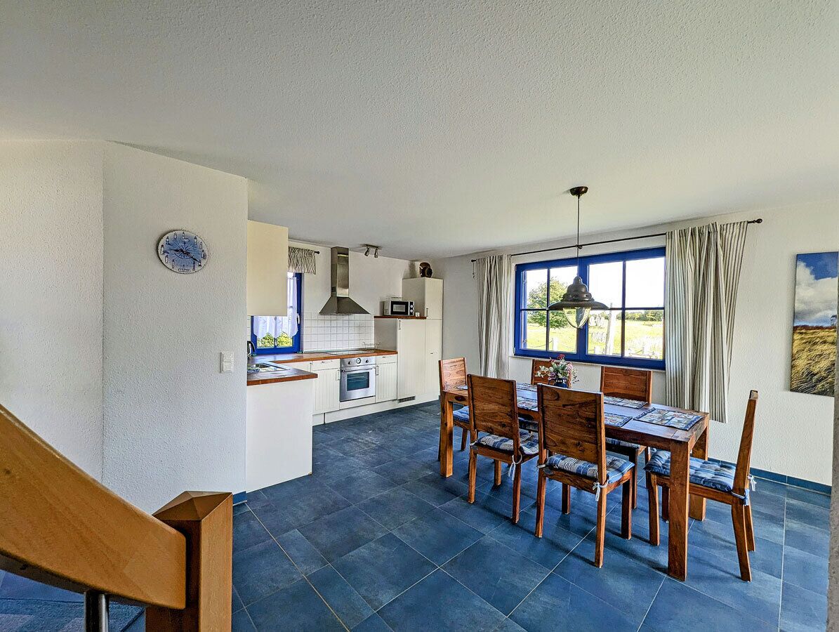 A modern kitchen with a dining area, a staircase, and a view of the outdoors.