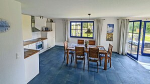 A spacious kitchen with a dining area, large windows, and a view of the outdoors. - Vacation home with a fireplace and an infrared sauna, about 200 meters from the sandy beach (Glowe)