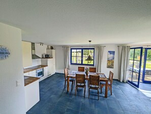 Eine geräumige Küche mit Essbereich, großen Fenstern und Blick ins Freie.