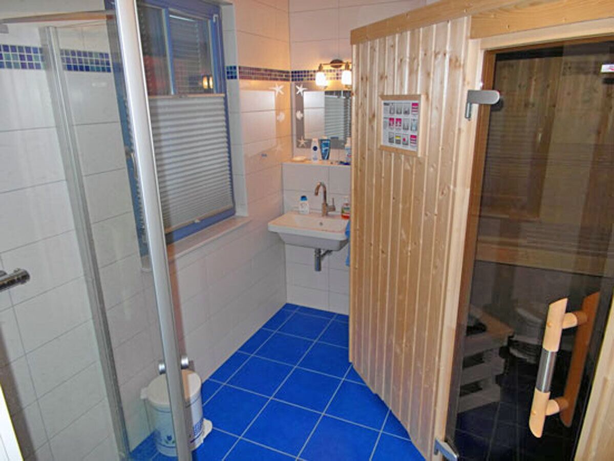 Ein Badezimmer mit Dusche, Waschbecken und Holztür.
