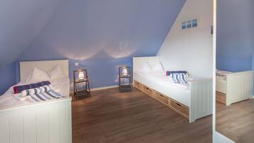 Une chambre avec deux lits, un plancher en bois et un plafond en pente.
