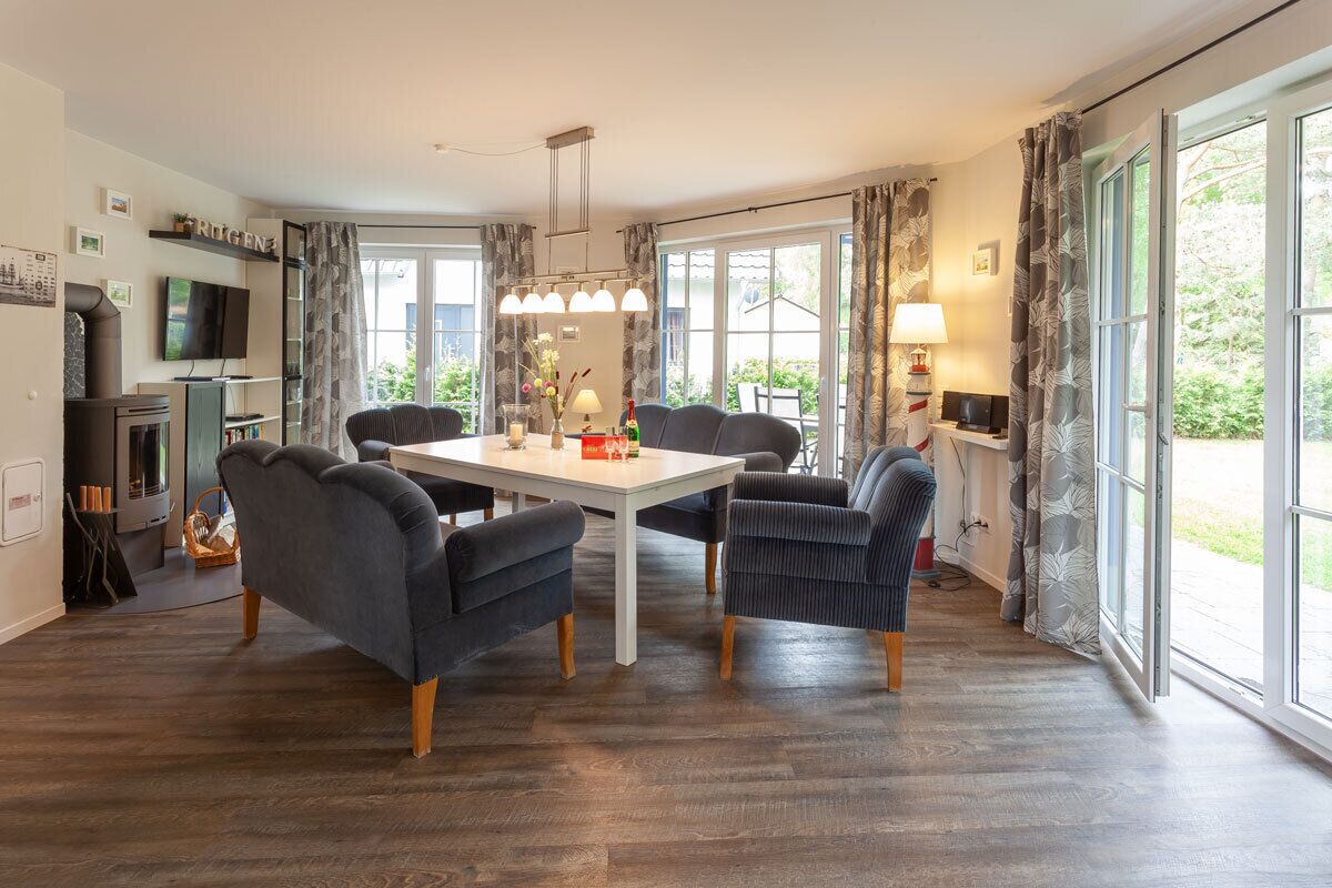 Un espace de salle à manger moderne avec une table blanche, des chaises à revêtement sombre et un lustre.