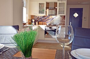 A dining area with a table set for two, a glass of water, and a potted plant. - Vacation home with a fireplace, about 400 meters from the sandy beach, 2 bedrooms, sleeps up to 5 people (Glowe)