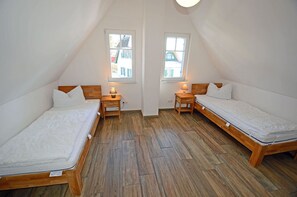 A room with two single beds, wooden nightstands, and a sloped ceiling. - Vacation home with a fireplace, about 400 meters from the sandy beach, 2 bedrooms, sleeps up to 5 people (Glowe)