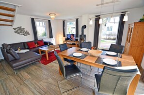 A modern living room with a sofa, dining table, and chairs, a fireplace, and a staircase. - Vacation home with a fireplace, about 400 meters from the sandy beach, 2 bedrooms, sleeps up to 5 people (Glowe)