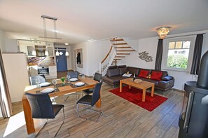 A modern living space with a dining area, a sofa set, a staircase, and a kitchen. - Vacation home with a fireplace, about 400 meters from the sandy beach, 2 bedrooms, sleeps up to 5 people (Glowe)
