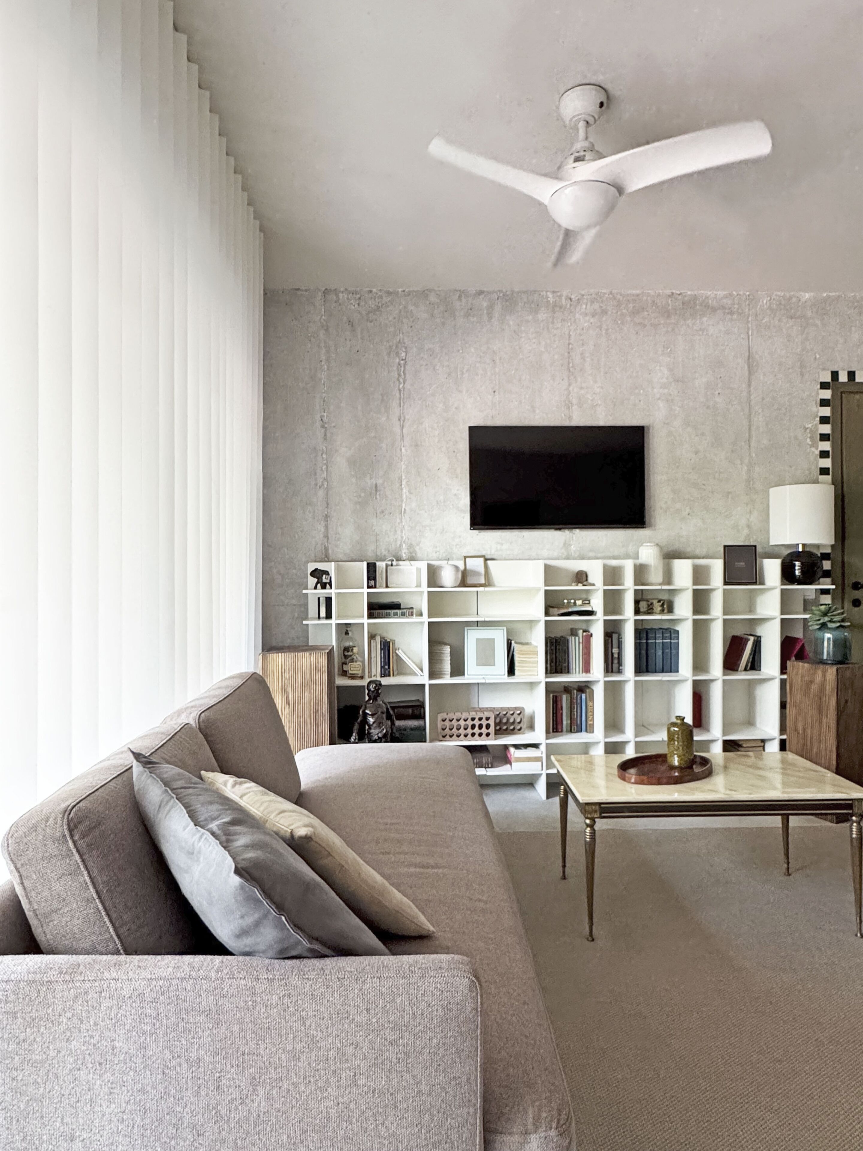 Un salon moderne comprenant un canapé, une table basse, une bibliothèque et un ventilateur de plafond.