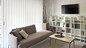 A living room with a sofa, coffee table, and a television mounted on a concrete wall. - La Bauhaus by Wonderful Italy (Desenzano del Garda)
