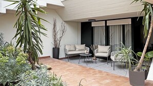 A modern outdoor patio with a seating area, potted plants, and a building with a sloped roof. - La Bauhaus by Wonderful Italy (Desenzano del Garda)